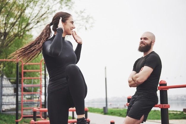 Young man and woman perform exercises and stretch marks before doing sports