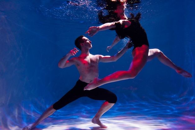 Giovane uomo e donna in posa insieme mentre sono immersi sott'acqua