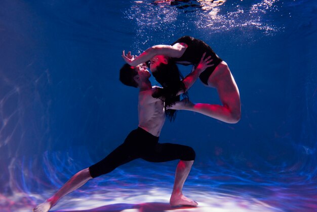 Young man and woman posing together while submerged underwater