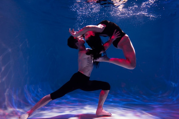 Young man and woman posing together while submerged underwater