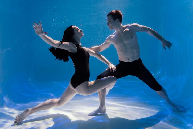 Young man and woman posing together while submerged underwater