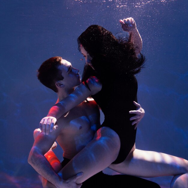 Young man and woman posing together while submerged underwater