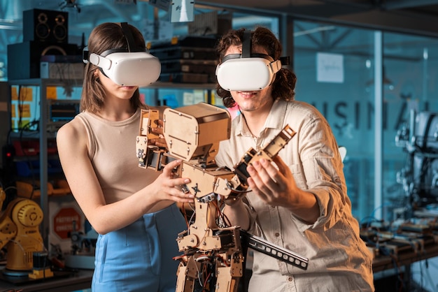 Free photo young man and woman in protective glasses doing experiments in robotics in a laboratory robot