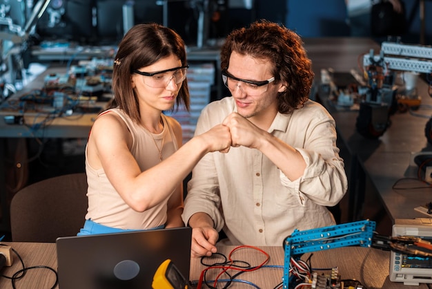 Free photo young man and woman in protective glasses doing experiments in robotics in a laboratory