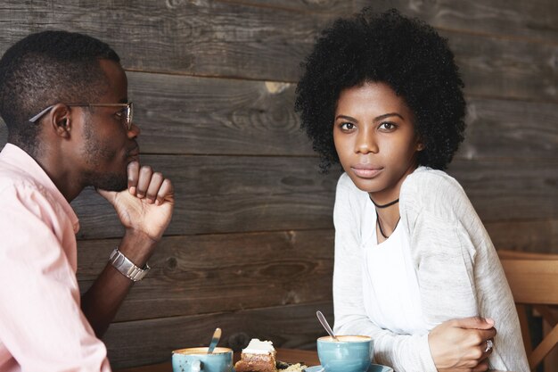 Молодой мужчина и женщина, сидя в кафе