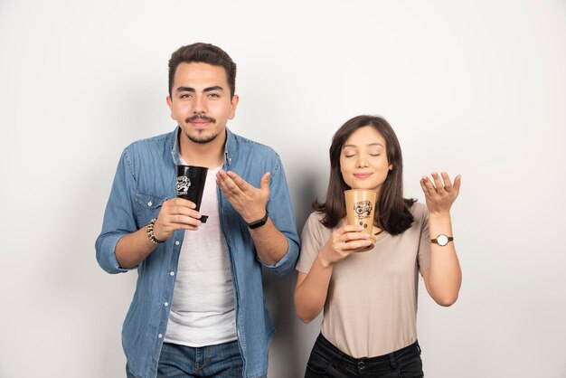 Young man and woman sniffs aroma coffee from cups.