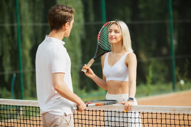 Young man and woman next to tennis net