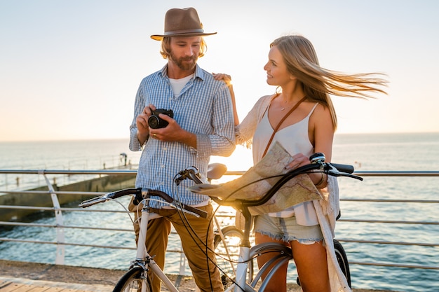 Foto gratuita giovane uomo e donna che viaggiano su biciclette tenendo la mappa