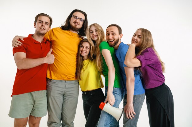 Young man and woman weared in LGBT flag colors on white wall. Caucasian models in bright shirts.