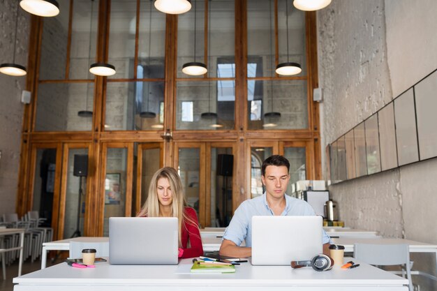 Young man and woman working on laptop in open space co-working office room