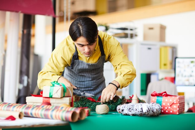 직장에서 젊은 남자, 크리스마스 화환 만들기 및 선물 포장