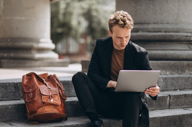 Young man working on a computer by the university