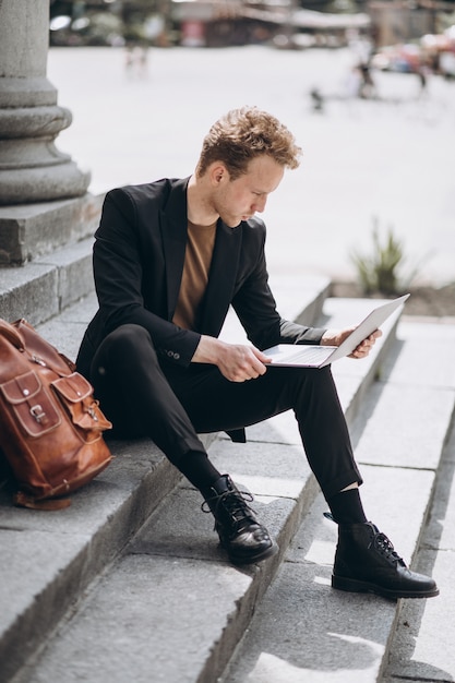 Young man working on a computer by the university