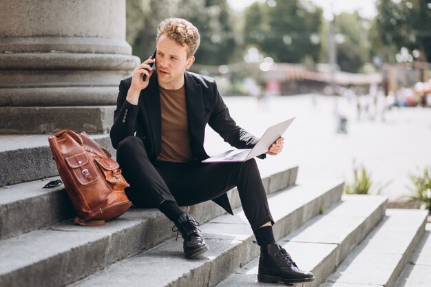 Young man working on a computer by the university