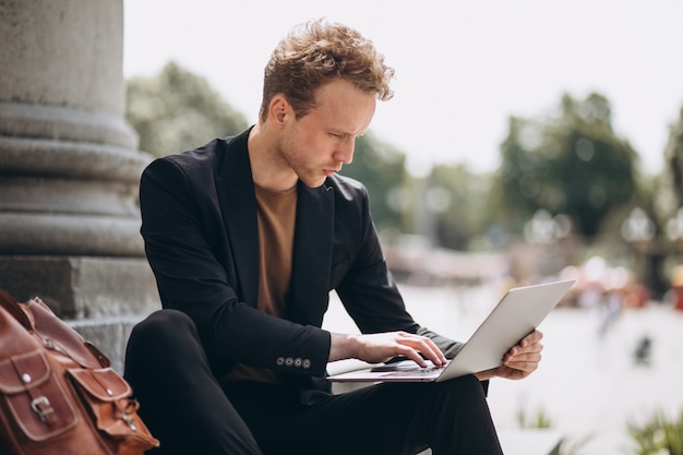 Young man working on a computer by the university