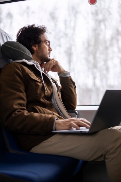기차로 여행하는 동안 노트북 작업을 하는 청년