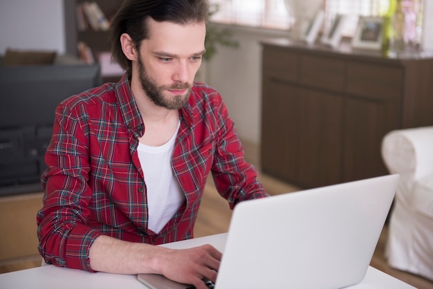 그의 노트북으로 집에서 일하는 젊은 남자