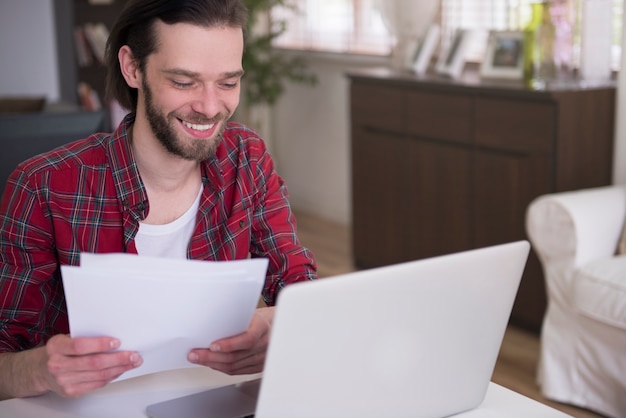 Foto gratuita giovane che lavora a casa con il suo laptop