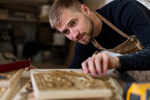 Молодой человек, работающий в мастерской гравировки по дереву