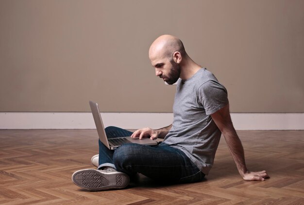 young man works on the computer sitting on the floor