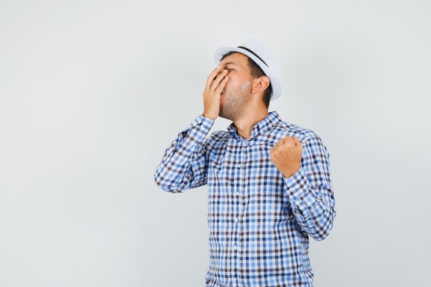 Young man yawning in checked shirt