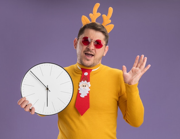 Free photo young man in yellow turtleneck and red glasses wearing funny red tie and rim with deer horns