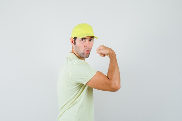 Young man in yellow uniform showing muscles of arm and looking strong 