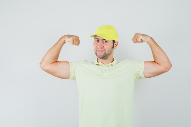 Young man in yellow uniform showing muscles of arms and looking powerful