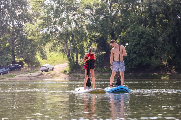 Young man  and a young woman paddle boarding on a river