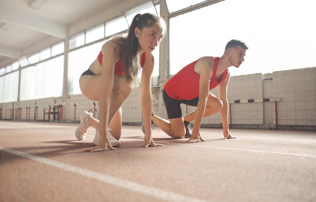 young man and young woman ready on the start of a track