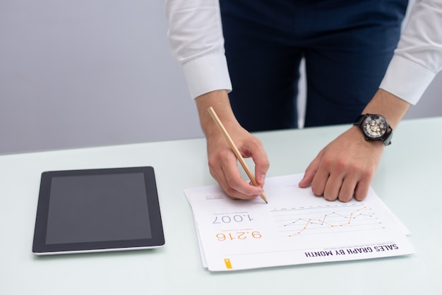 Young marketing manager writing notes on report in office