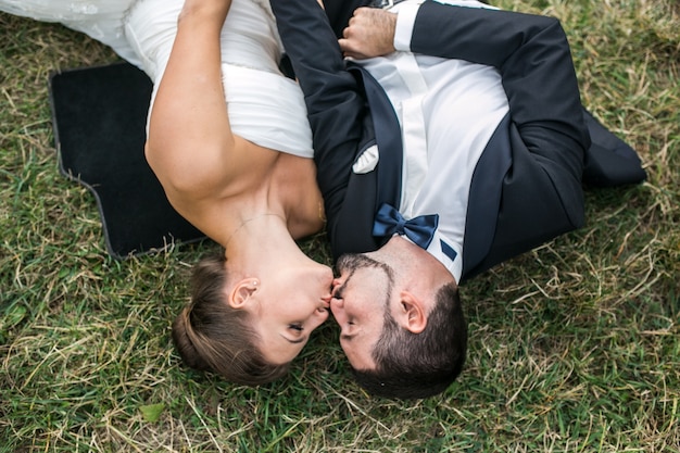 Foto gratuita giovane coppia sposata sdraiato sul prato baciare