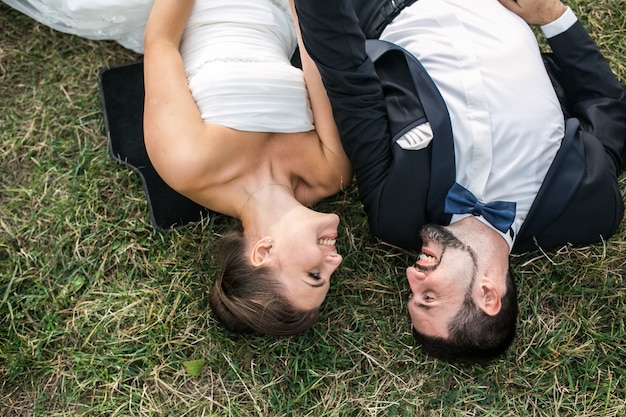 Free photo young married couple lying on the lawn looking their eyes