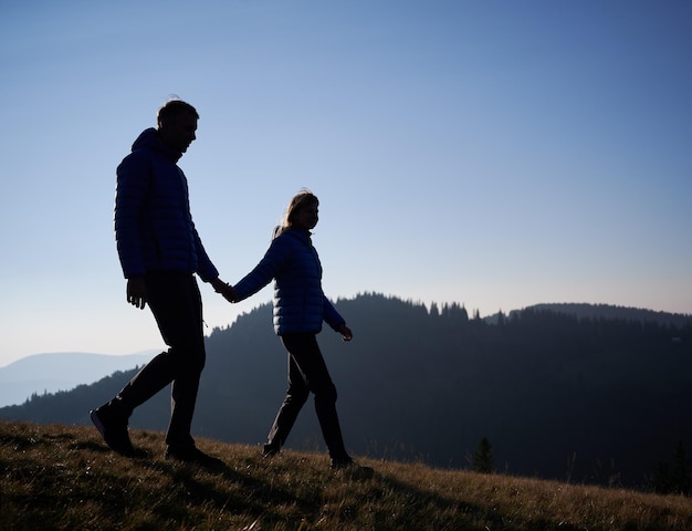 Young married pair walking in mountains at noon in sunny day