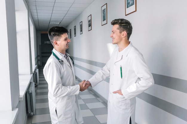 Young medics shaking hands in hallway