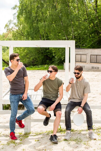 Young men drinking beer on beach