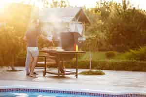 Free photo young men roasting barbecue on grill in cottage countryside.