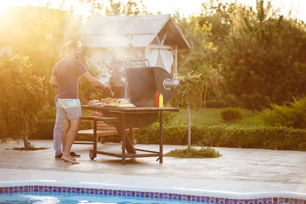 Young men roasting barbecue on grill in cottage countryside.