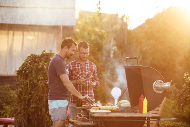 Young men roasting barbecue on grill in cottage countryside.