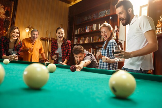 Young men and women playing billiards at office after work.