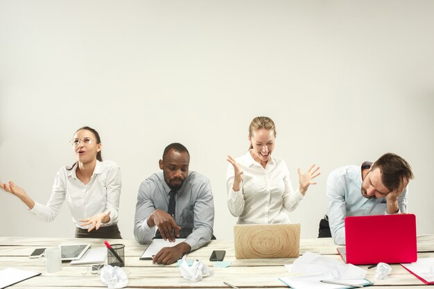 Young men and women sitting at office and working on laptops. Emotions concept