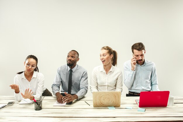 Young men and women sitting at office and working on laptops. Emotions concept