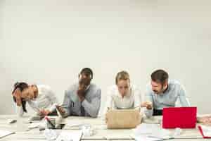 Foto gratuita giovani uomini e donne seduti in ufficio e lavorando su laptop. concetto di emozioni