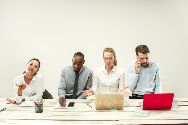 Foto gratuita giovani uomini e donne seduti in ufficio e che lavorano su laptop.