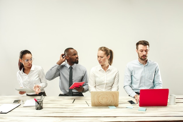 Foto gratuita giovani uomini e donne seduti in ufficio e che lavorano su laptop.