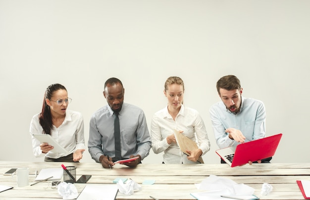 Foto gratuita giovani uomini e donne seduti in ufficio e che lavorano su laptop.