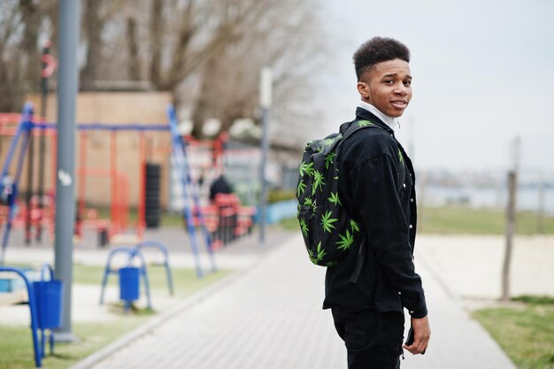 街を歩く若いミレニアル世代のアフリカの少年マリファナのバックパックジェネレーションZの概念を持つ幸せな黒人男性