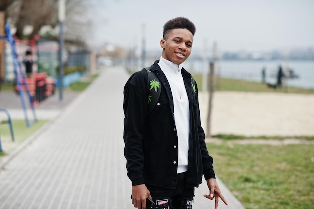 Молодой африканский мальчик-миллениал гуляет по городу Счастливый темнокожий мужчина с рюкзаком с марихуаной Концепция поколения Z