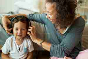 Free photo young mixed race mother babysitting her adorable three year old son, using wireless headset