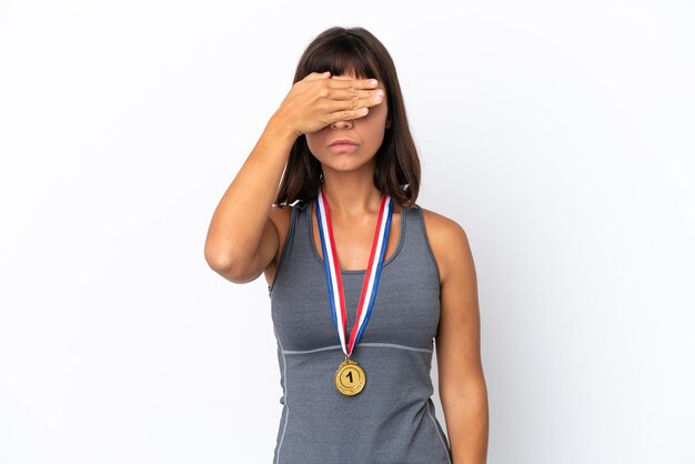 Young mixed race woman with medals isolated on white background covering eyes by hands. do not want to see something